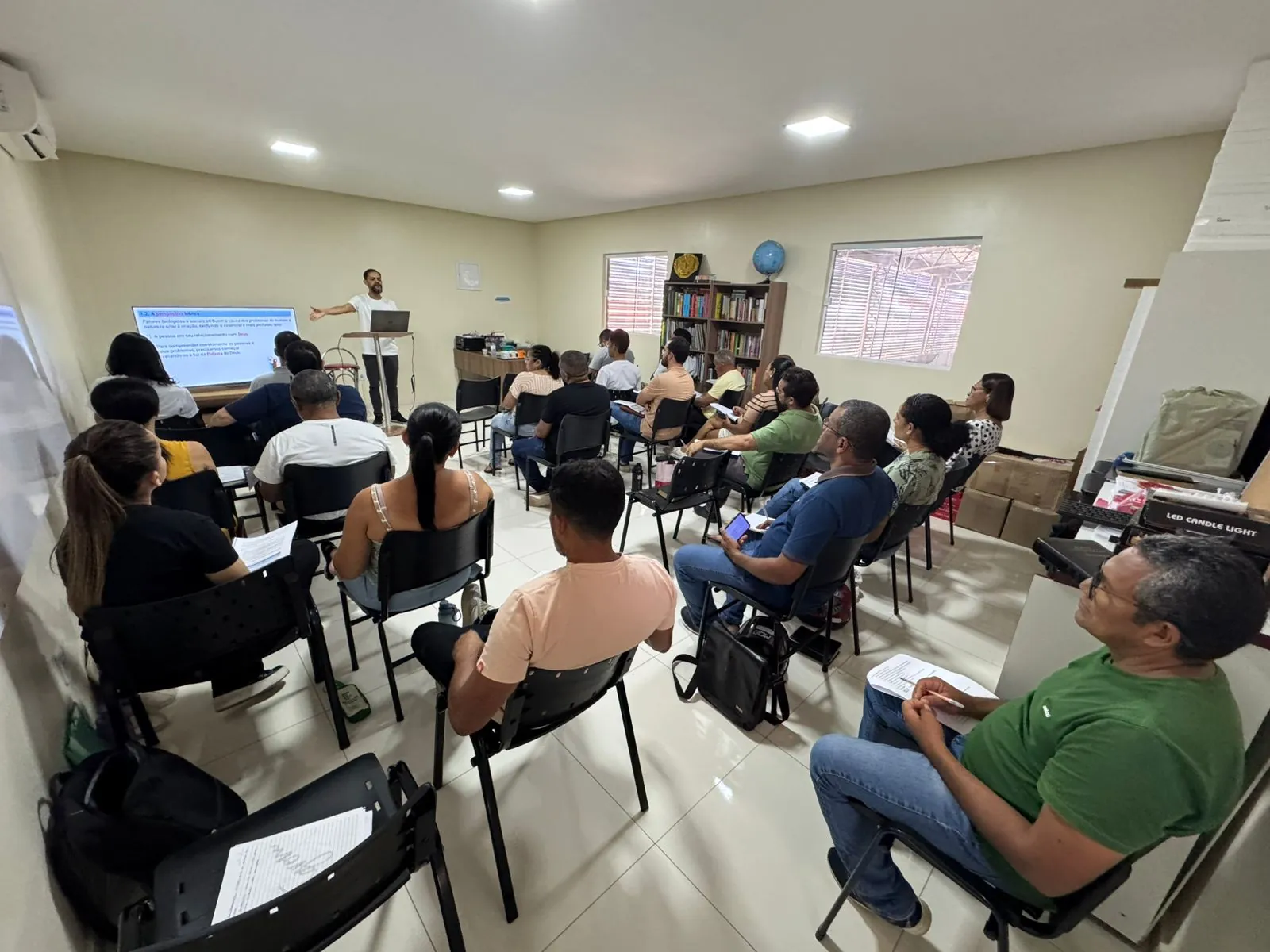 Turma de Floriano (PI) na aula de Pressuposições do Aconselhamento Bíblico: o professor Jandro Ferreira, em pé ao fundo, apresenta slides em uma tela, e vários alunos adultos assistem sentados em cadeiras